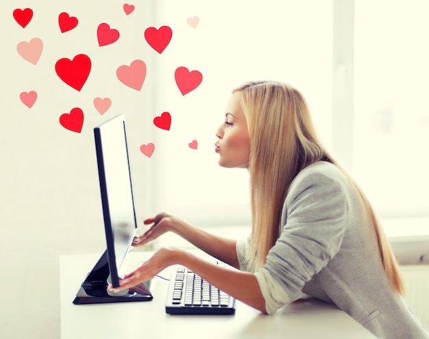 virtual relationships, online dating and social networking concept - woman sending kisses with computer monitor