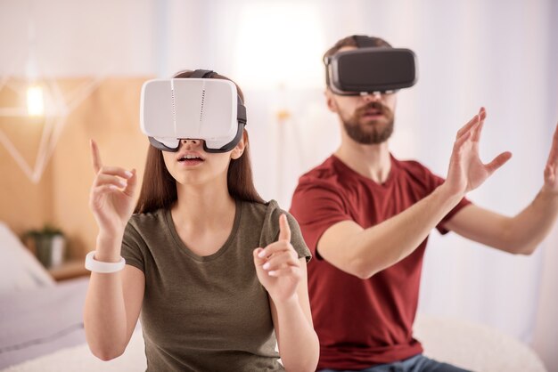 가상 세계. VR 안경을 쓰고 입을 벌리면서 손을 드는 창의적인 아름다운 여인