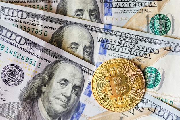 Virtueel geld gouden bitcoin op honderd dollar biljetten achtergrond Wissel bitcoin contant in voor een dollar