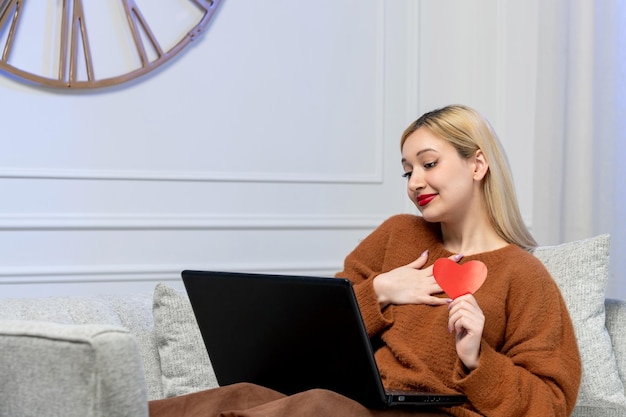 Virtuele liefde schattig jong blond meisje in gezellige trui op computer afstand datum heerlijk lachend