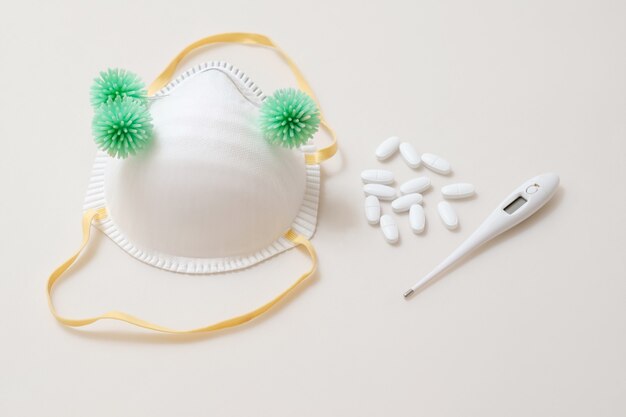 Virus bacteria on medical mask with thermometer and pilles tablets on the table