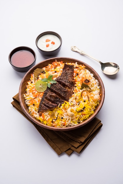 Vis Biryani of visrijst - populair Indiaas niet-vegetarisch recept gemaakt van vis gemarineerd met Indiase kruiden, verse kruiden en gekookt met basmatirijst, selectieve focus