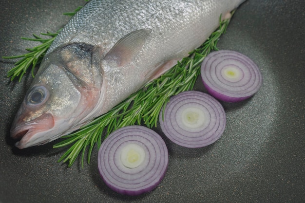 Vis wordt bereid om te koken in een pan met rozemarijn en kruiden