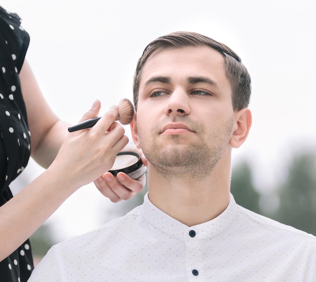 Visagist doet make-up voor een jonge man