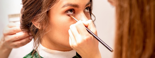 Visagist en kapper bereiden de bruid voor om kapsel en make-up te maken in een schoonheidssalon