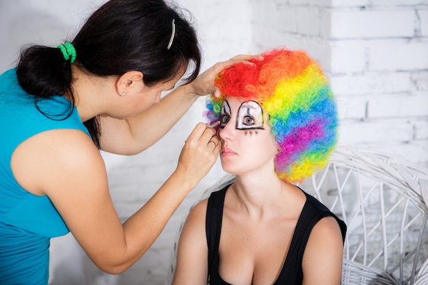 Visagist zet meisje clown make-up in de studio