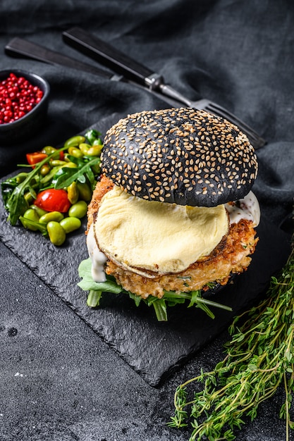 Visburger met zwarte briochebroodjes, omelet, viskotelet en rucola. bovenaanzicht