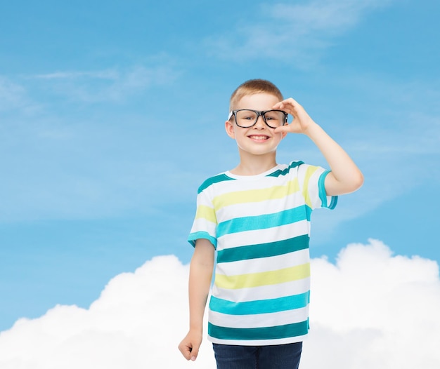 visie, onderwijs, jeugd en school concept - glimlachend jongetje in bril over blauwe lucht met witte wolk achtergrond