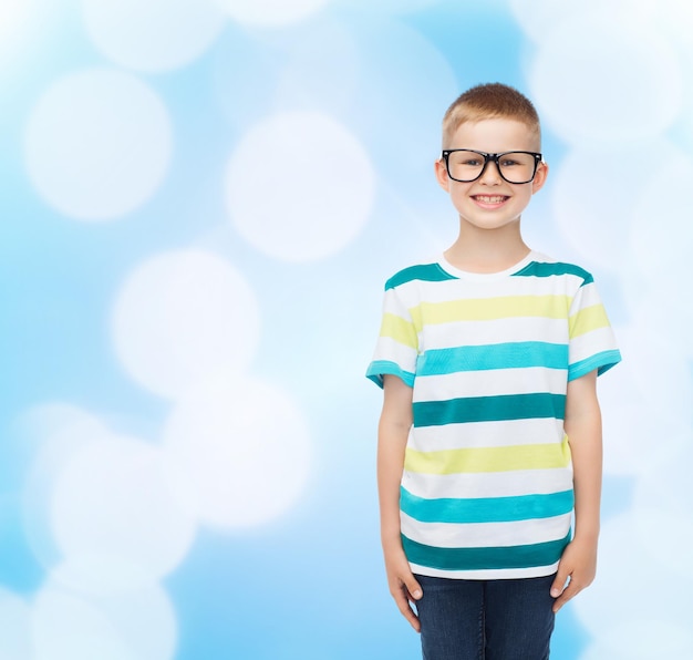 vision, education and school concept - smiling little boy in eyeglasses over blue background