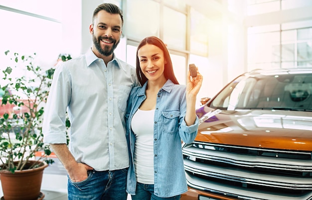 Посетите автосалон Счастливая молодая пара выбирает и покупает новый автомобиль для семьи