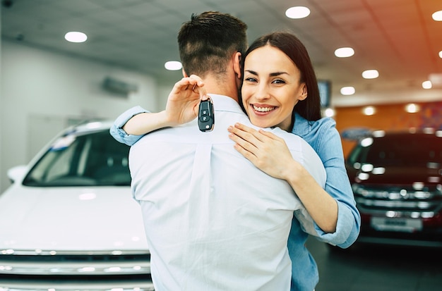 Посетите автосалон Счастливая молодая пара выбирает и покупает новый автомобиль для семьи