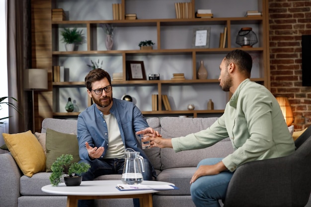 Visit to a psychologist a man sits on a couch and talks to a psychotherapist the patient is depresse