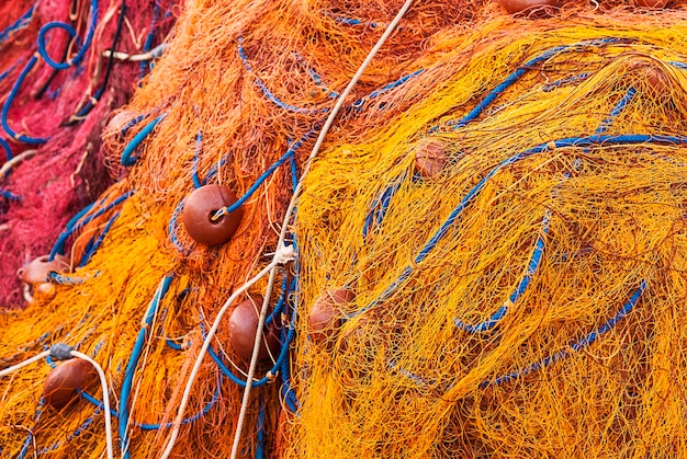 Visnet van oranje en gele touwen en stapel boeien op het dok.