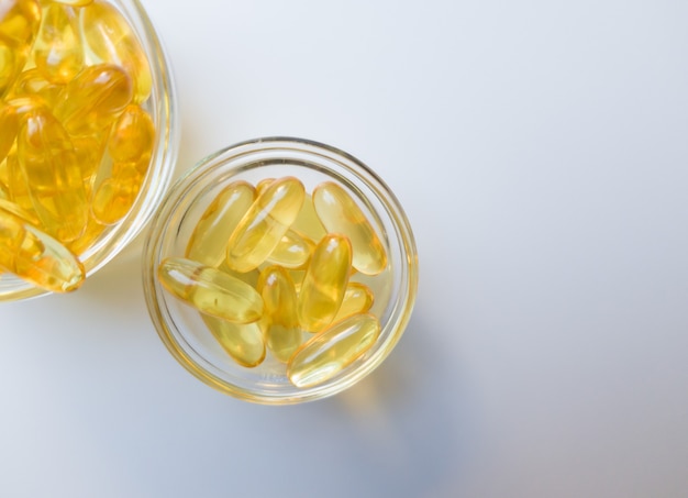 Visoliecapsules op een glasplaat. Veel vitamine omega 3 op een witte achtergrond. Close-up, bovenaanzicht, product met hoge resolutie. Metabolisme in het lichaam. Het lichaam van calcium. Een snelle manier om gewicht te verliezen