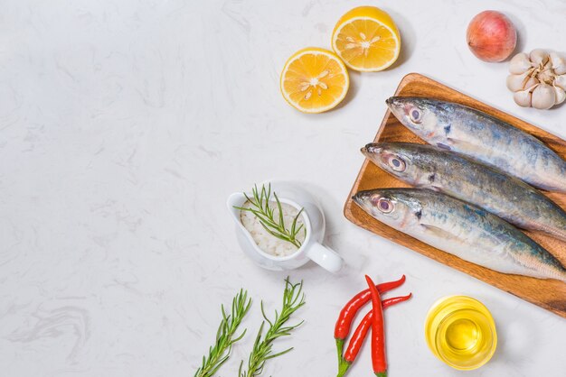 Visschotel koken met verschillende ingrediënten. Verse rauwe vis versierd met plakjes citroen en kruiden op houten tafel.