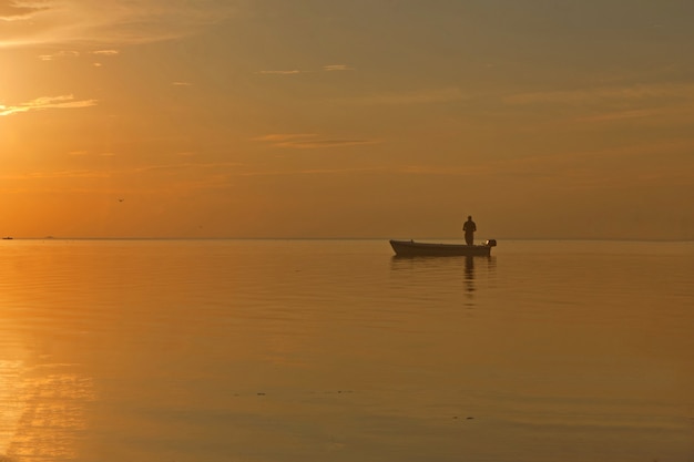 visser bij de boot op gouden zonsondergang zee mooi en romantisch zonsondergang silhouet met boot