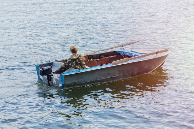 Visser op een oude motorboot, die vist naar het Teletskoye-meer, Republiek Altai.