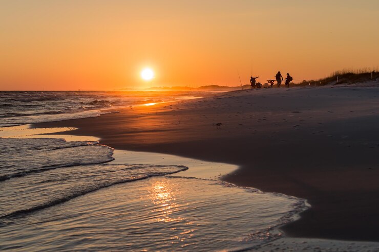 Foto visser op het strand tegen de hemel bij zonsondergang