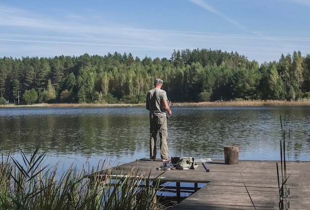 Visser op houten steiger die vissen op haspelstaaf in de zomer vangt