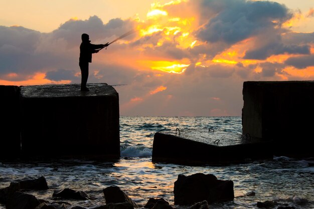 Visser op pier bij zonsondergang