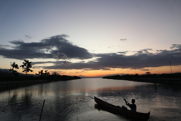 Visser op zijn boot bij zonsondergang. Vissersboot bij zonsondergang