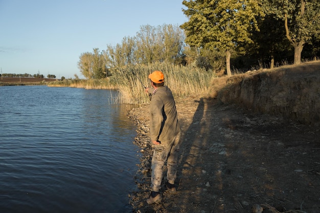 Visser staat aan de rivier en probeert een vis te vangen Sportrecreatie levensstijl