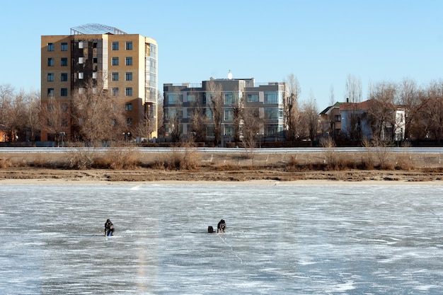 Vissers vangen vis op het ijs van een bevroren rivier die in de winter vist