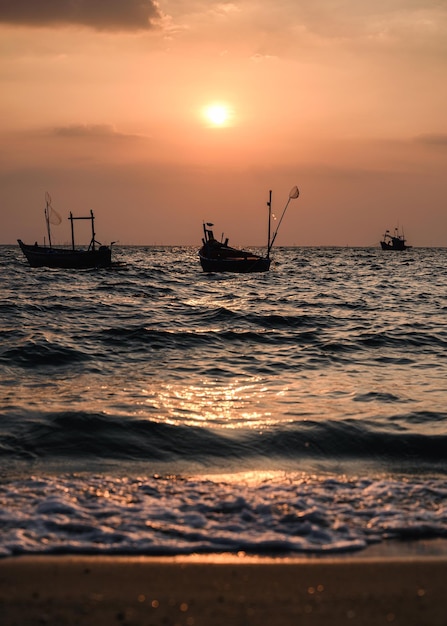 Vissersboot drijvend op tropisch zeestrand bij zonsondergang