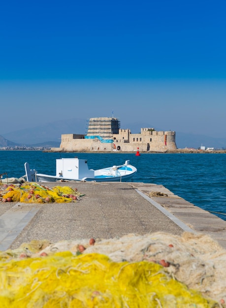 Vissersboot en netten met Bourtzi-kasteel op achtergrond Nafplio Griekenland