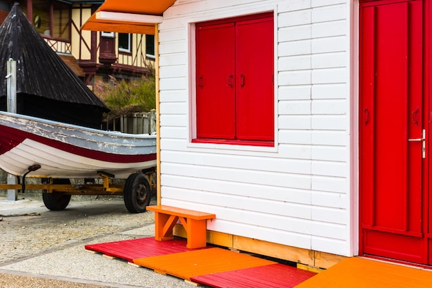 Vissersboot in de buurt van wit houten landhuis met een rode deur en raam