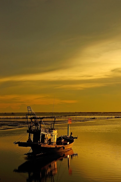 Vissersboot met het milieu van de zonsonderganghemel