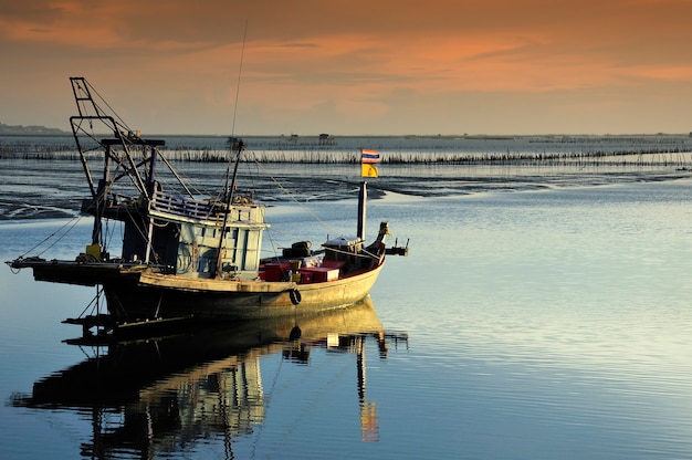 Vissersboot met het milieu van de zonsonderganghemel