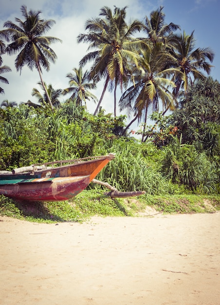 Vissersboot op een tropisch strand met palmbomen