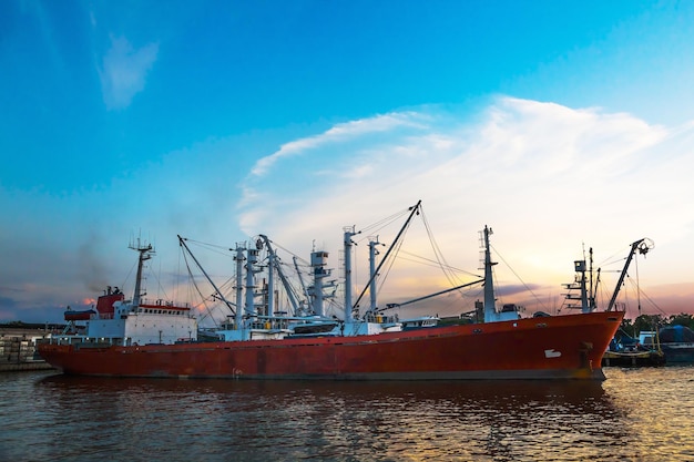 Vissersboten liggen afgemeerd in de zeehaven tegen de achtergrond van zonsondergang