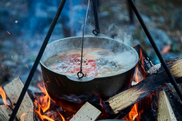 Vissoep koken in de opgeborgen bowler boven een kampvuur.