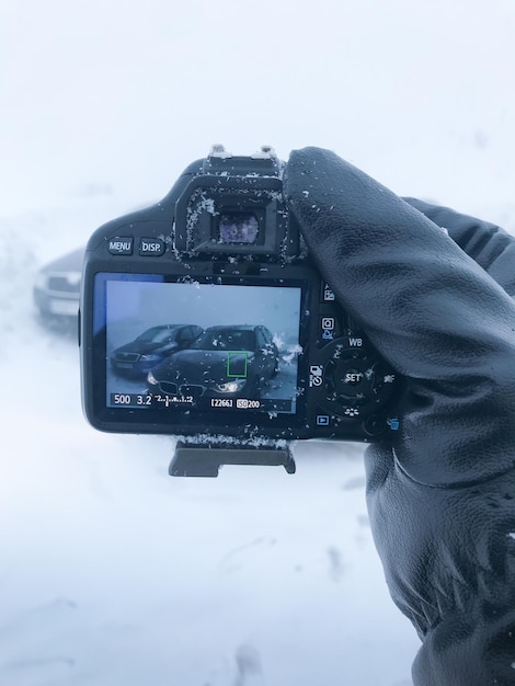 Vista en primera persona de un fotografo con su camara disparando a un coche en la nieve