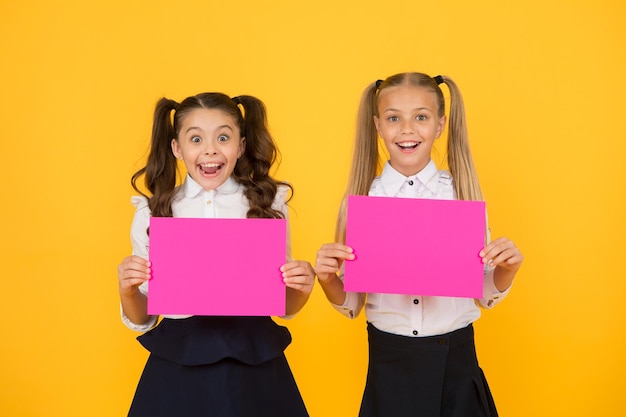 Concetto di comunicazione visiva amicizia scolastica ragazze uniformi scolastiche tenere poster le ragazze della scuola mostrano poster spazio di copia poster sociali la socializzazione coinvolge il modo in cui i bambini vanno d'accordo tra loro