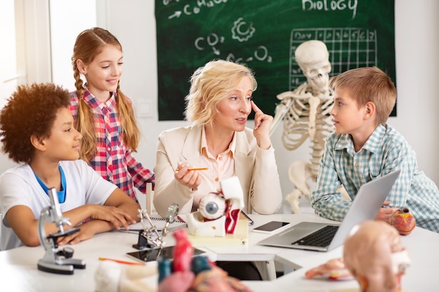 Photo visual representation. pleasant nice woman pointing at her eye while explaining how it works