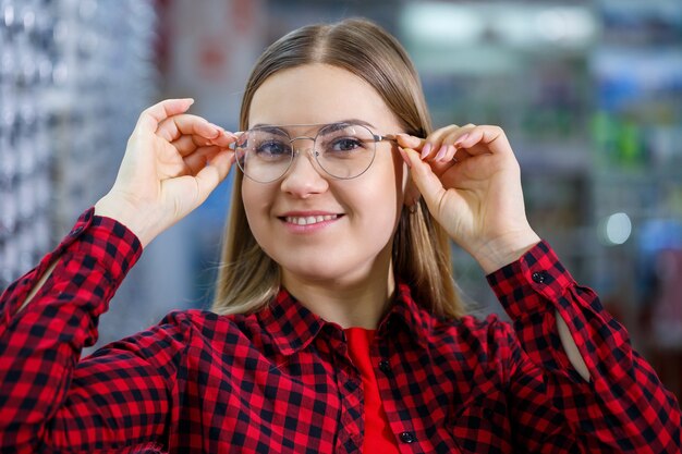 A visually impaired girl chooses glasses. She is wearing a shirt and a beautiful smile.