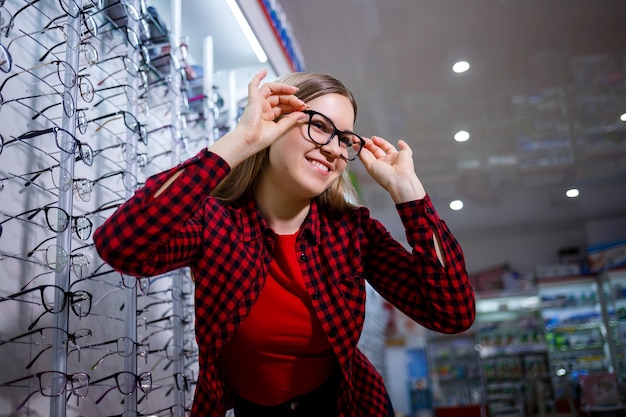 A visually impaired girl chooses glasses. She is wearing a shirt and a beautiful smile.