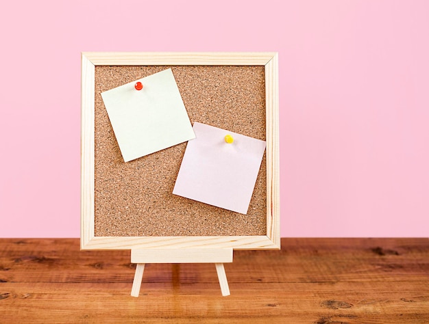 visueel bord met lege plaknotities op houten tafel en roze achtergrond