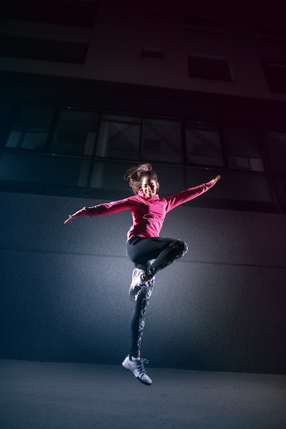 Photo vital sporty young woman jumping against black wall.