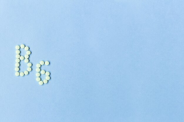 Vitamin B6 pills forming the word B6 over turquoise background