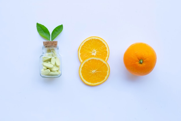 Photo vitamin c bottle and pills with orange fruit on white.