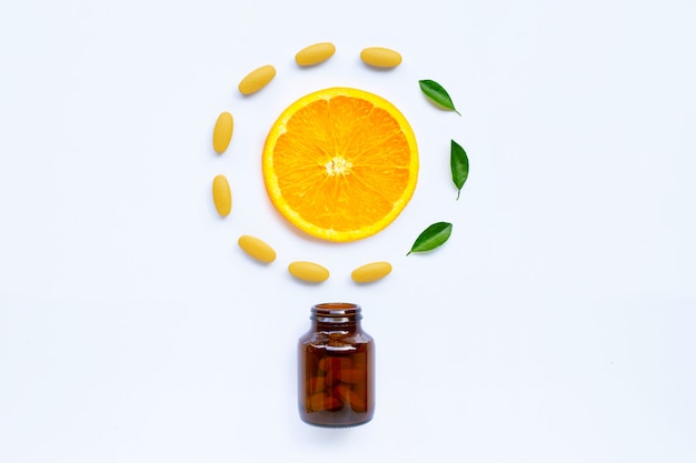 Vitamin C bottle and pills with orange fruit on white 