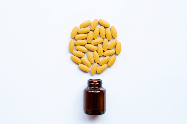 Vitamin C bottle and pills with orange fruit on white 