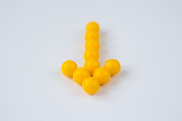 Vitamin C capsules in the form of arrow on white background