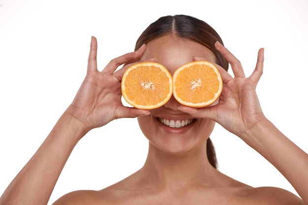 비타민 C는 피부에 좋습니다 반으로 자른 오렌지를 눈 위에 들고 있는 아름다운 젊은 여성의 사진