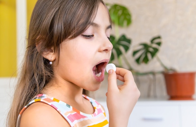 Vitamin c pill to her child. dietary supplements for kids. selective focus. people.