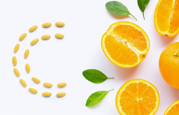 Foto pillole della vitamina c con gli agrumi arancio freschi isolati